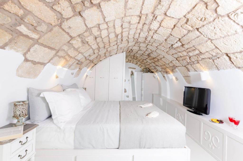 a bedroom with a white bed with a stone ceiling at Tholos Deluxe House in Astypalaia Town