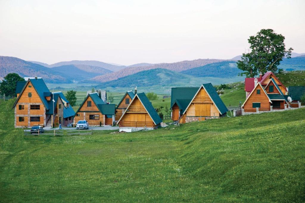 um grupo de casas numa colina num campo em Holiday Home Vile Calimero em Žabljak