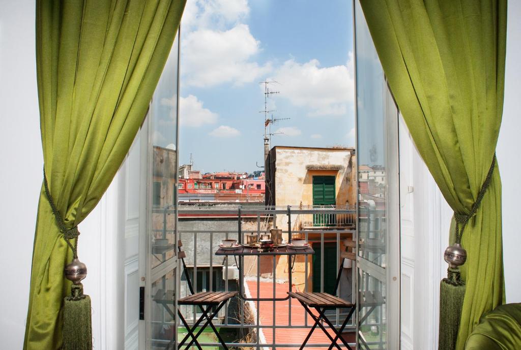 balcón con cortinas verdes y vistas a la ciudad en Art12 B&B, en Nápoles