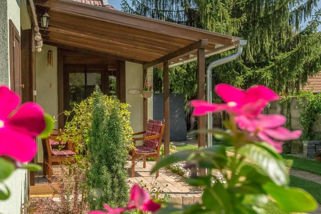 a patio with a wooden pergola and pink flowers at Csillagvirág Apartman Gyula in Gyula