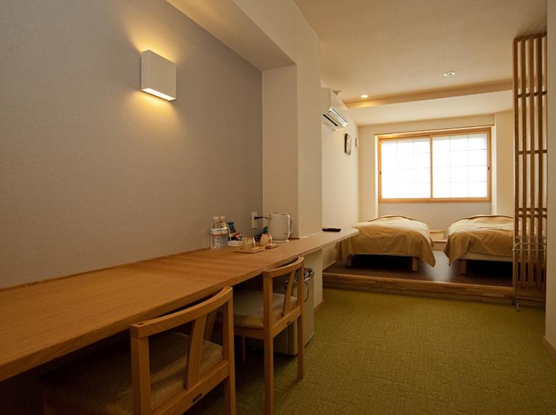 Habitación con escritorio y dormitorio con 2 camas. en Mizuhasou en Miyajima