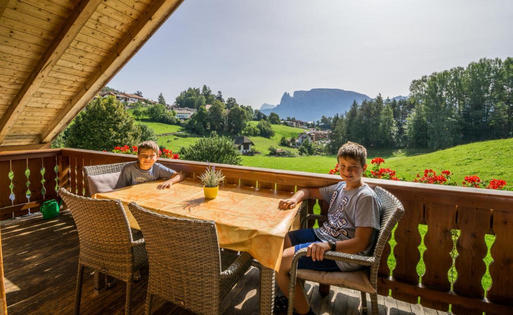 dos jóvenes sentados en una mesa en una cubierta en Appartments Neuhof, en Collalbo