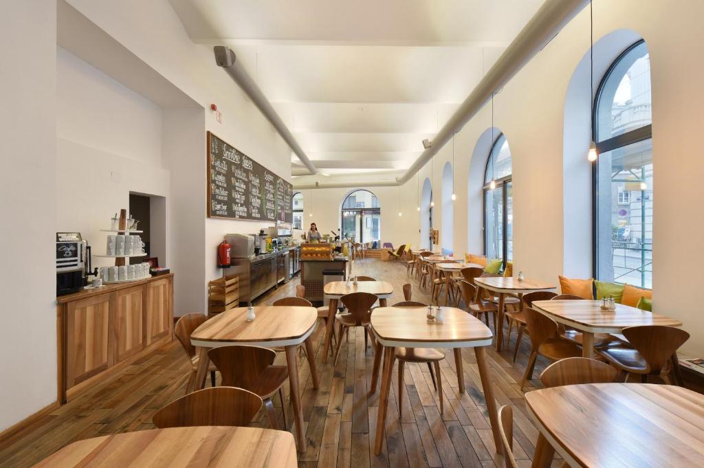 um restaurante com mesas e cadeiras de madeira e janelas em Hotel Mocca em Viena