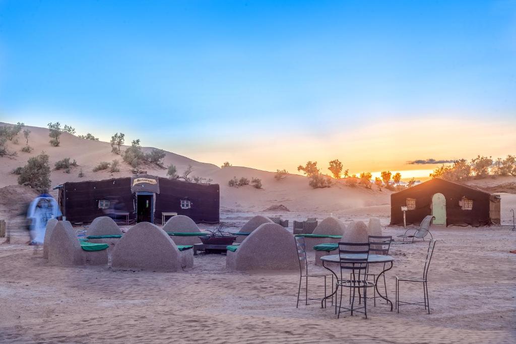 een groep tafels en stoelen in de woestijn bij Bivouac Rêve Sahara-Dar Azawad in Mhamid