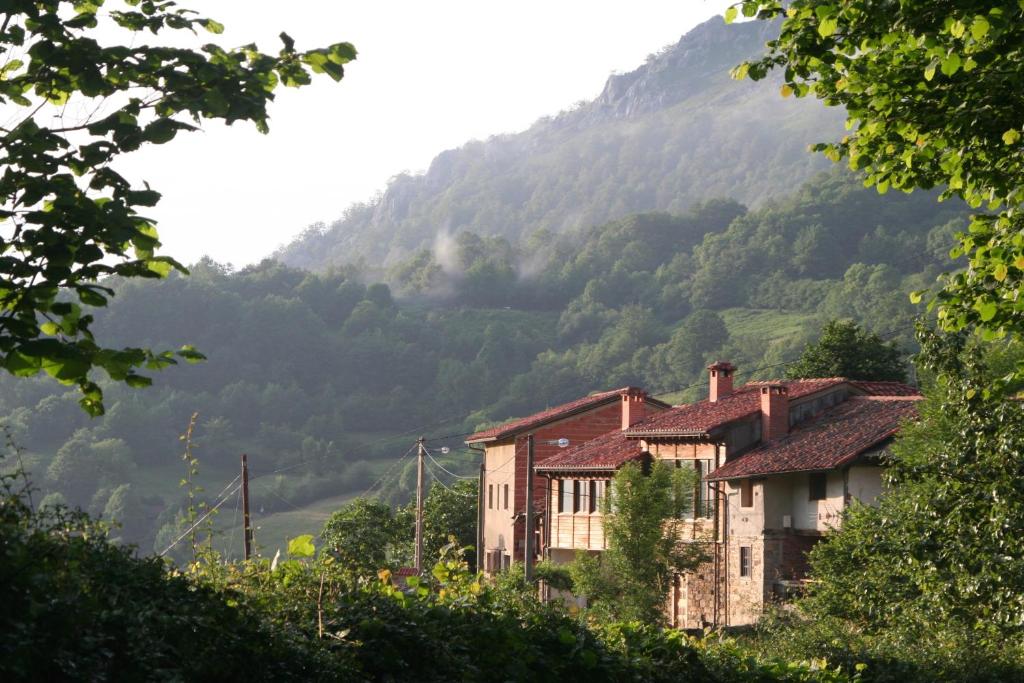 una casa vieja frente a una montaña en Albergue Les Xendes. Parque de Redes en Caso