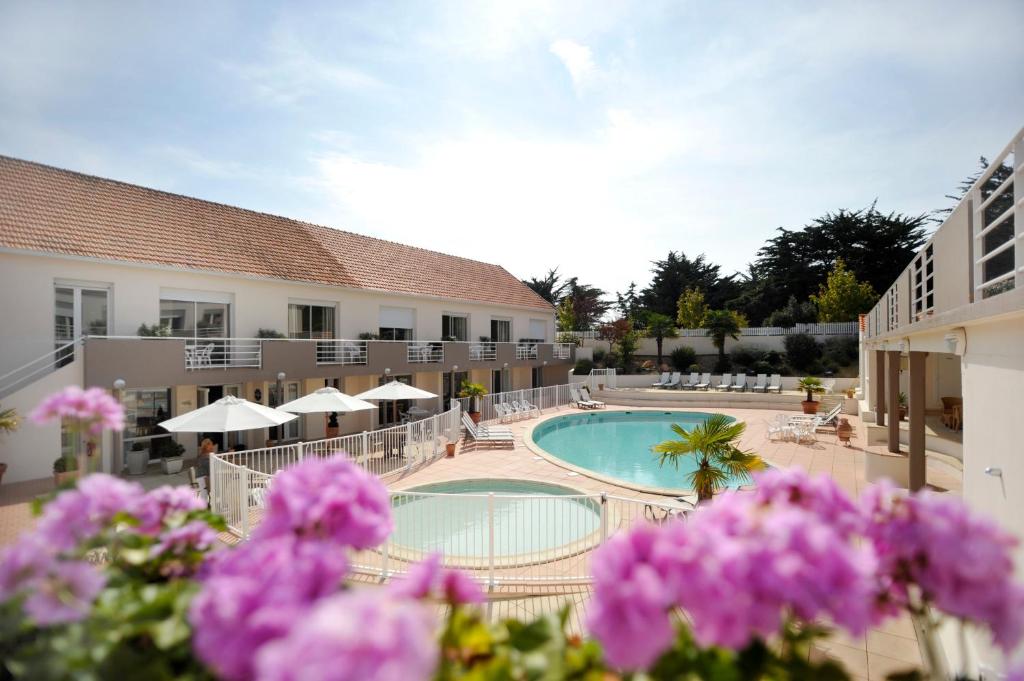 a hotel with a swimming pool and purple flowers at Résid'Azur in Saint-Jean-de-Monts