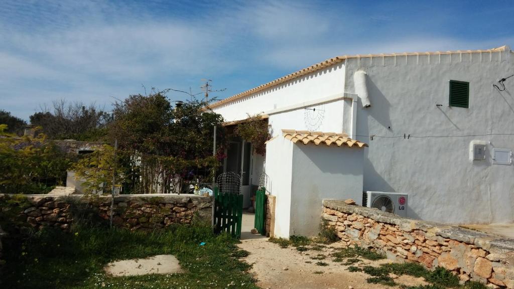 Biały dom z kamienną ścianą obok w obiekcie Can Xumeu Miquel w mieście Sant Ferran de Ses Roques