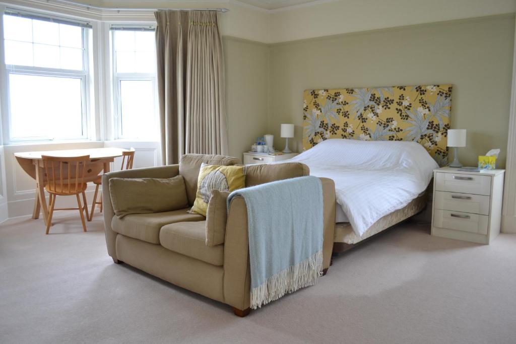 a bedroom with a bed and a couch and a chair at Burnside Farm B & B in Girvan