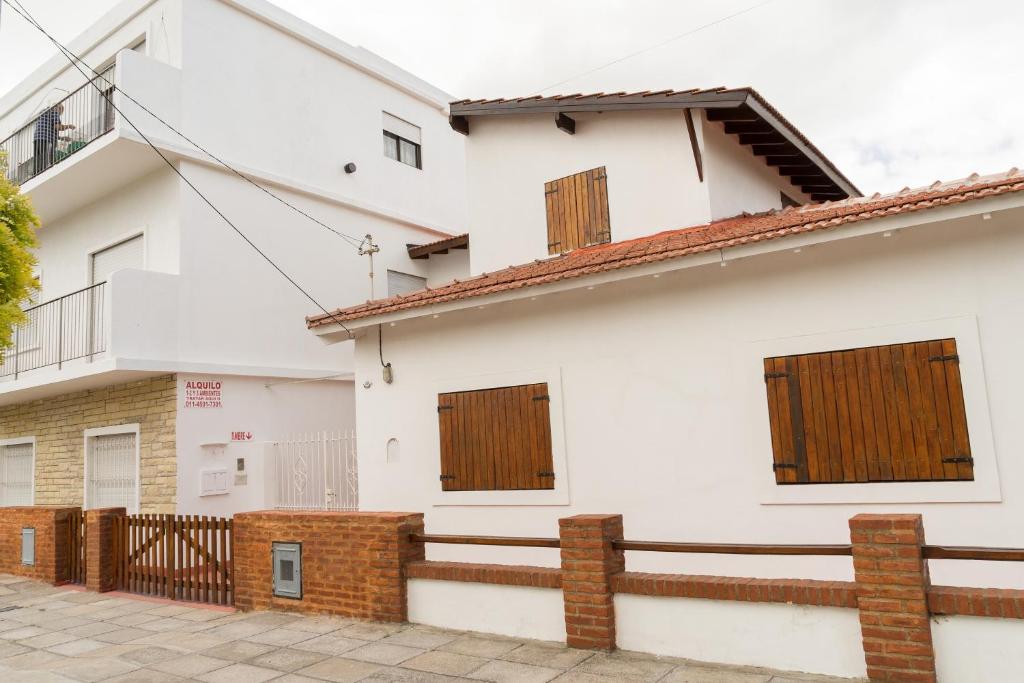 Casa blanca con puertas de madera y valla en Departamentos VILLAHERMOSA de Un Dormitorio - Dos Dormitorios y Monoambientes en San Clemente del Tuyú