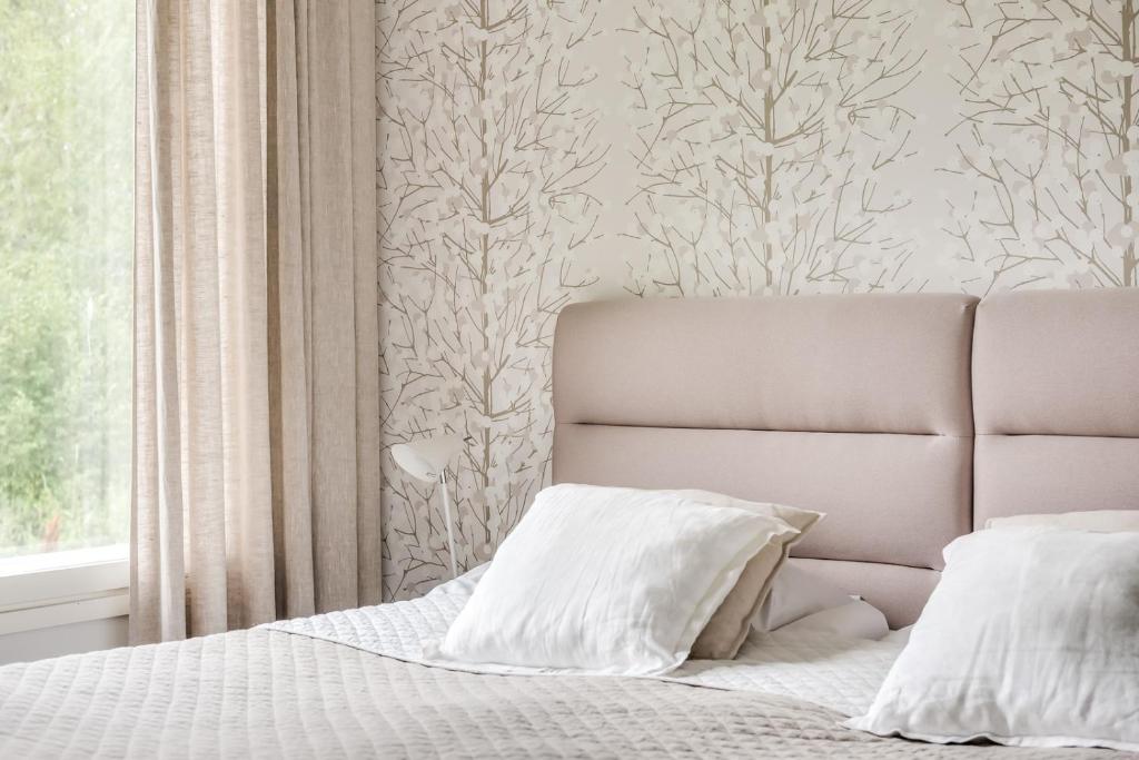 een slaapkamer met een bed met witte kussens en een raam bij Apartment Kievarinhovi in Kempele