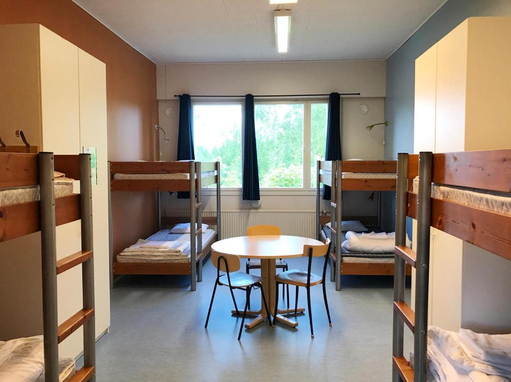 Zimmer mit einem Tisch und 2 Etagenbetten in der Unterkunft Godby Vandrarhem in Godby