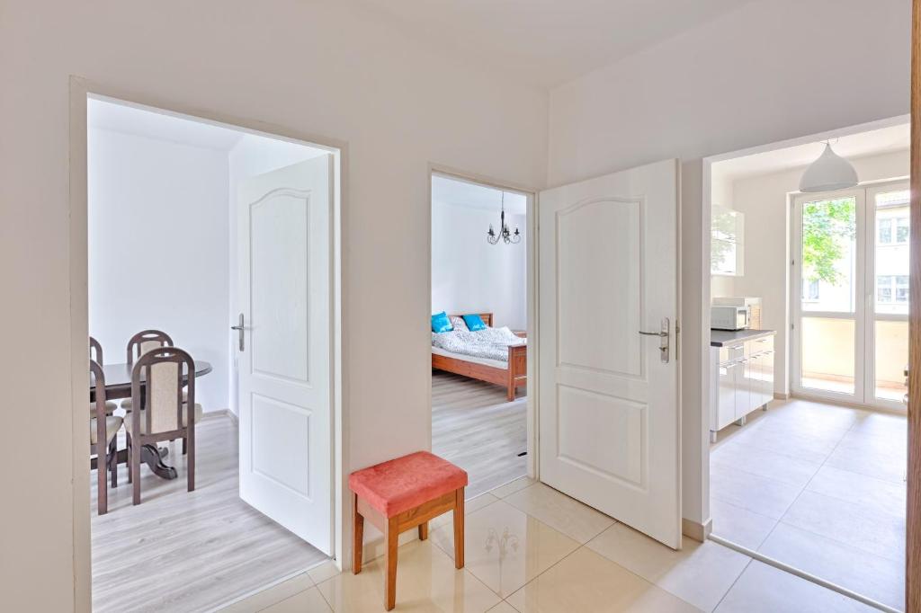 シュチェチンにあるMoMi Apartament Blonia Szczecin Herbowaの白いドアと赤い椅子が備わる部屋