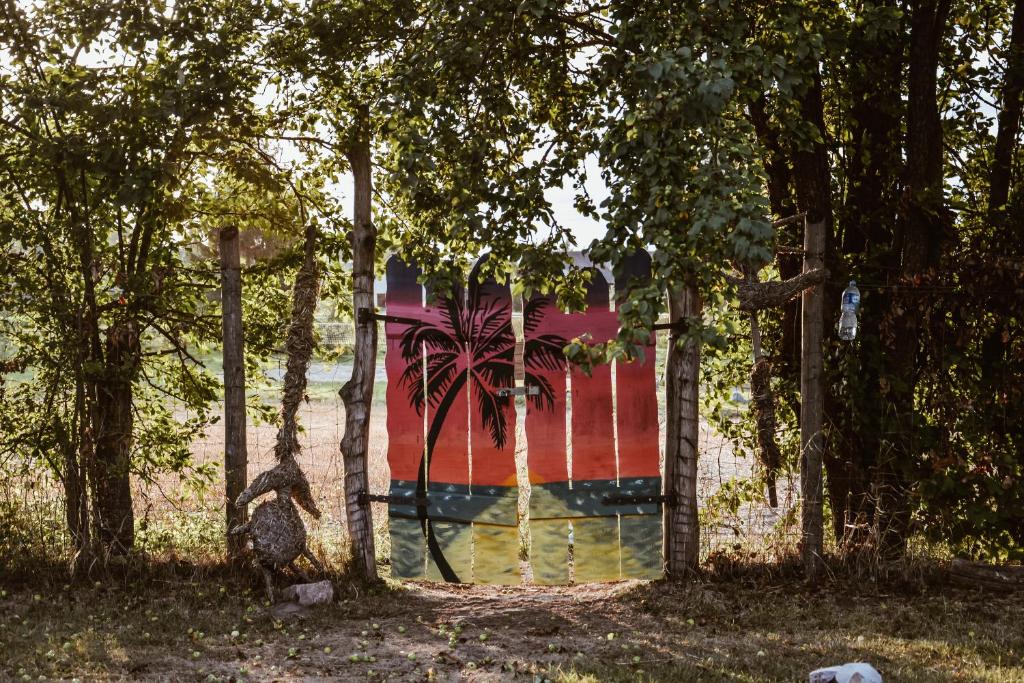 a wall with a painting of a palm tree on it at Sunny Nights Homestead Rustic House in Gataučiai