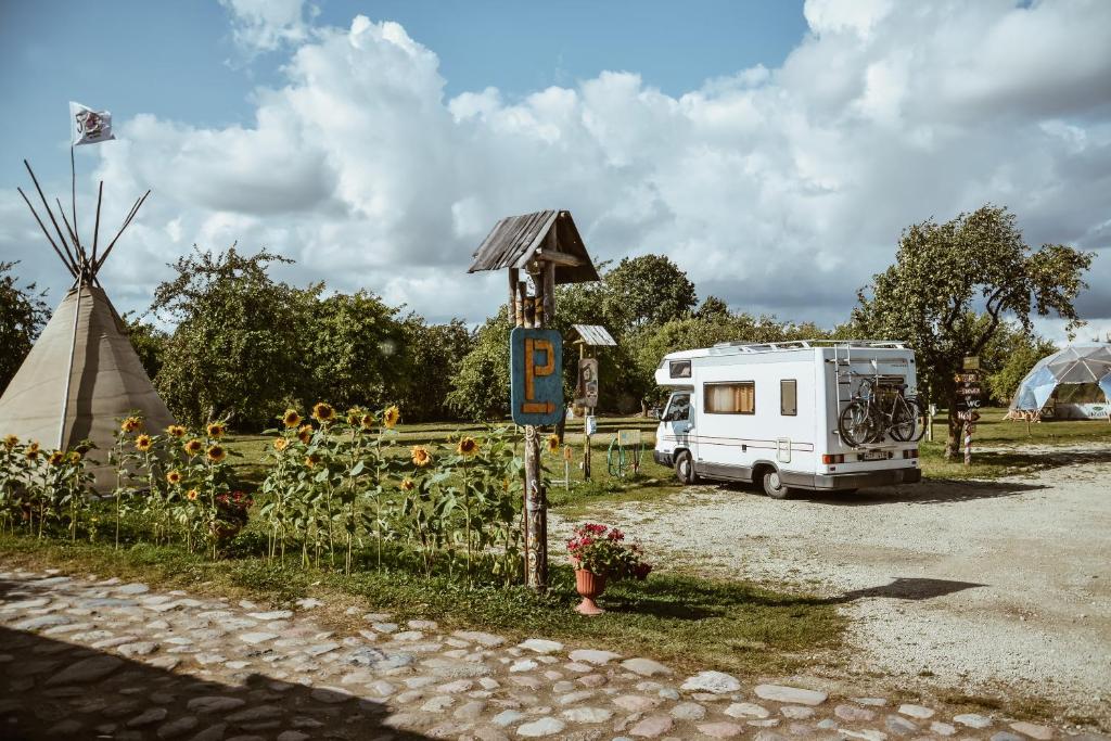 an rv parked in a parking lot next to a windmill at Sunny Nights Homestead Rustic House in Gataučiai