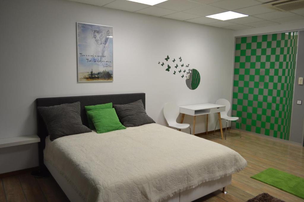a bedroom with a bed and a table and a green wall at Vasarely Luxury Flat in Satu Mare