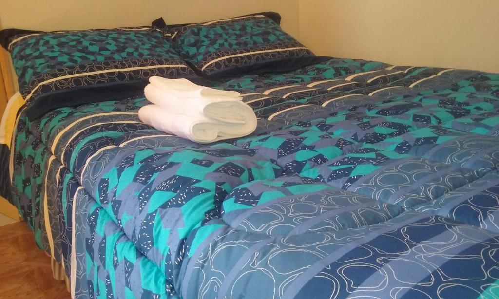 a blue bed with a pile of towels on it at Casa Blanca Hospedaje in Mejillones