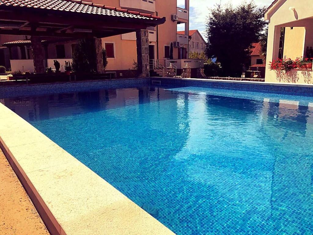 a large blue swimming pool in front of a house at Apartments Hanka in Njivice