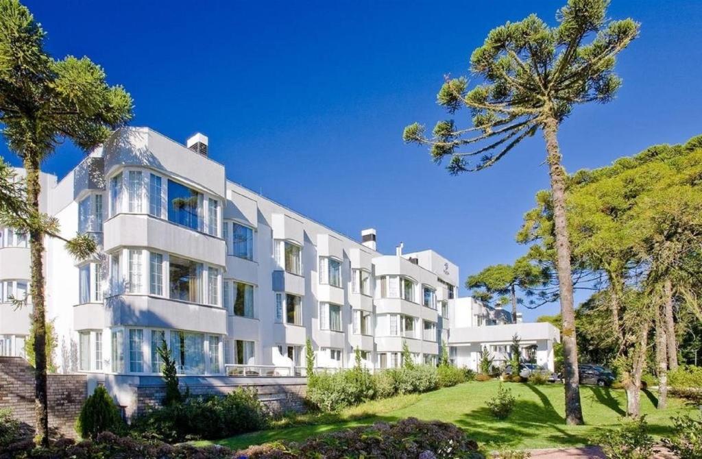 un gran edificio blanco con palmeras delante en Flat Luxo Mountain Village, en Canela