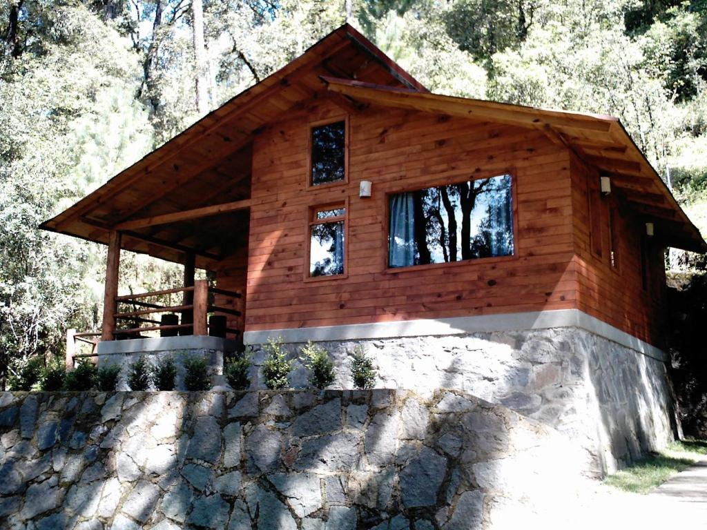 a log cabin with windows on a stone wall at Cabañas Alpinas López Fontes in Valle de Bravo