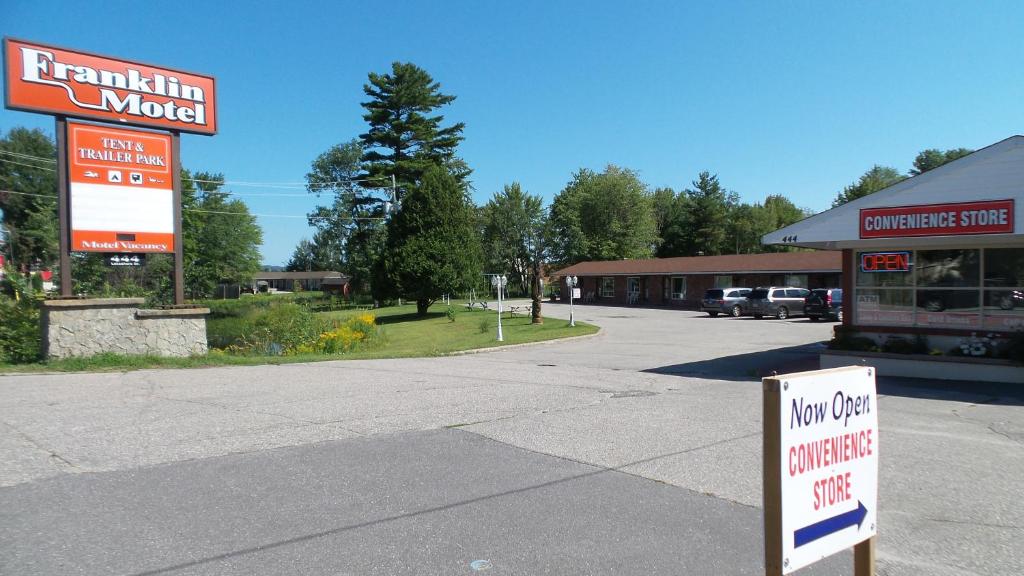 una señal frente a un edificio con un concesionario de automóviles no utilizado en Franklin Motel, Tent & Trailer Park, en North Bay