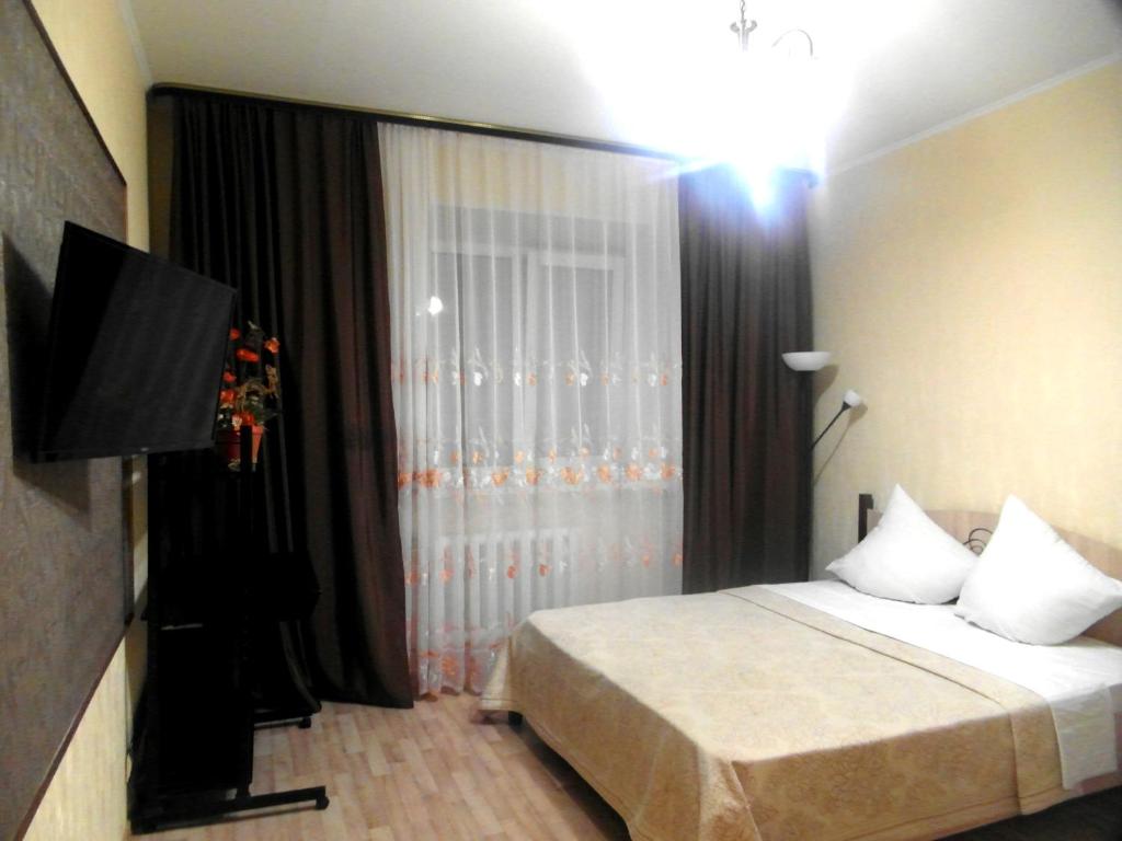 トムスクにあるКварт отель Надежда Московский тракт 6/3のベッドとテレビが備わるホテルルームです。