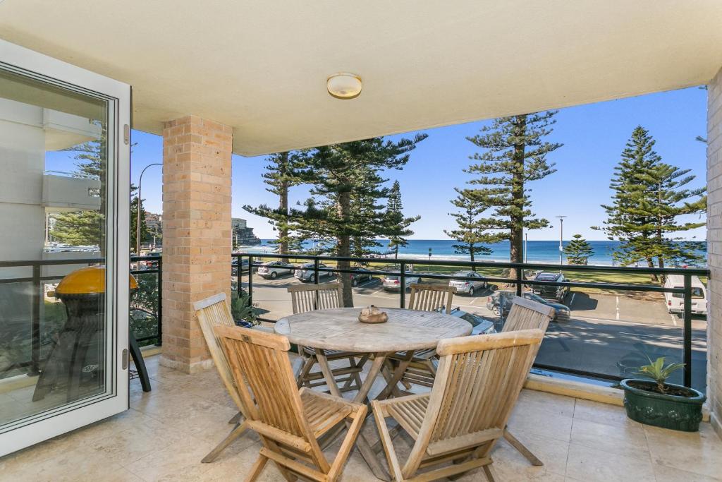 een tafel en stoelen op een patio met uitzicht op de oceaan bij Beachfront on Golden Mile in Sydney