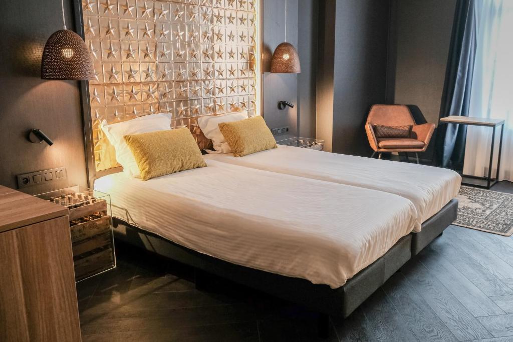 um quarto com uma cama grande e uma cadeira em Hotel Brouwerij Het Anker em Mechelen