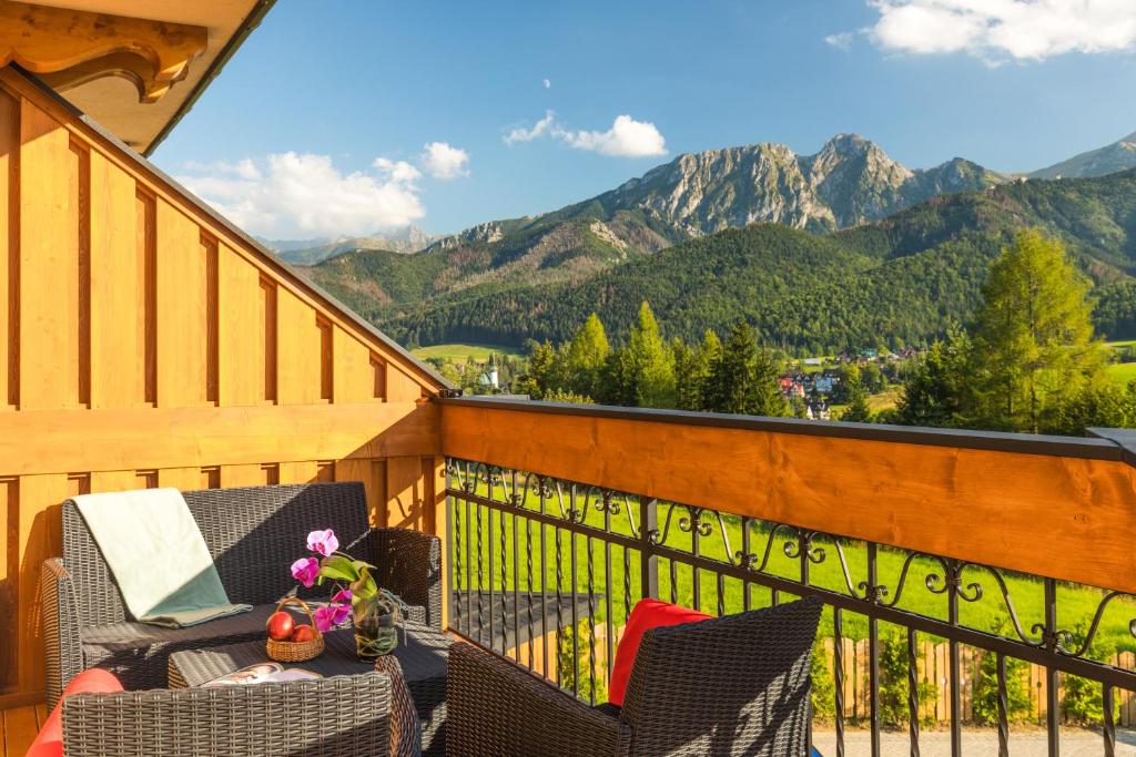 a balcony with a table and chairs and mountains at Apartamenty Rockus LUX & SPA Zakopane in Kościelisko
