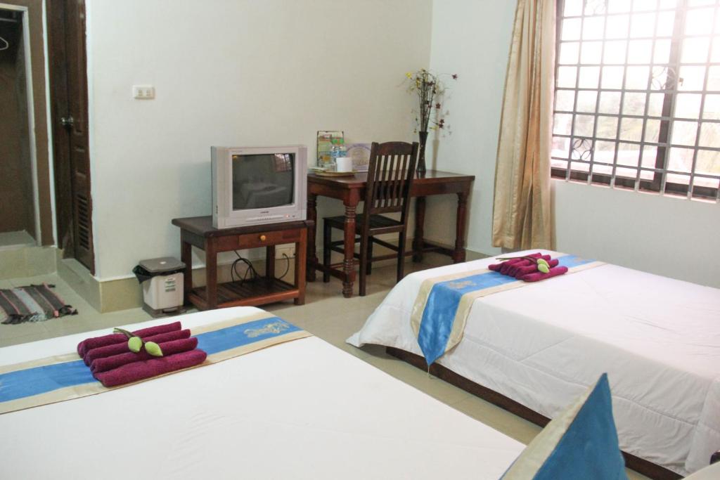 Habitación con 2 camas, TV y escritorio. en Tropical Breeze en Siem Riep