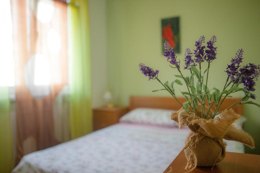 a vase of purple flowers on a table in a bedroom at Apartment Elanda Downtown in Zadar