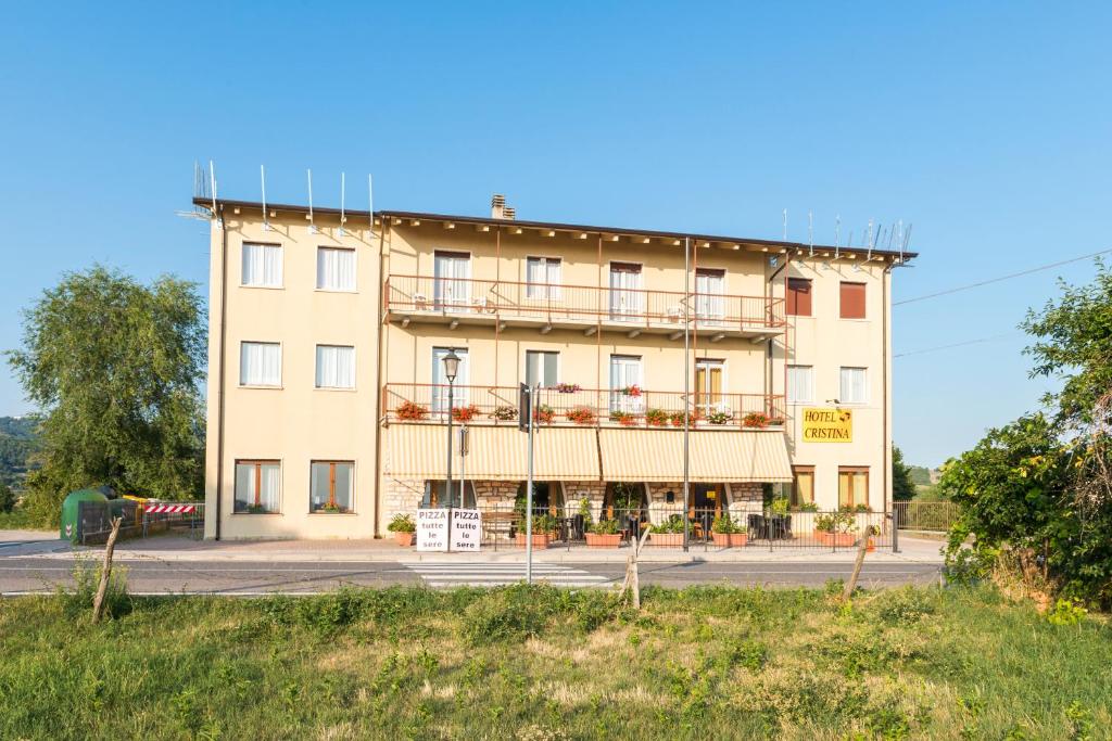 a large tan building with balconies on a street at Hotel Cristina in San Rocco di Piegara