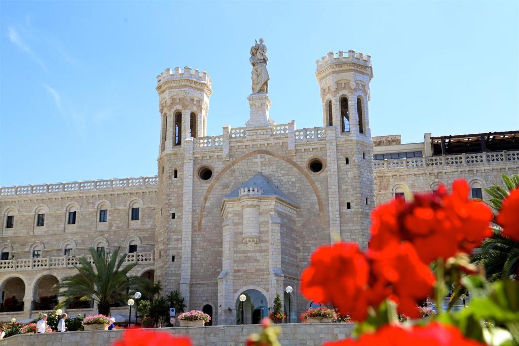 a building with red flowers in front of it at Notre Dame Center in Jerusalem