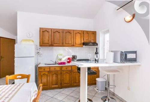 a kitchen with wooden cabinets and a white refrigerator at Natura A1 in Medulin