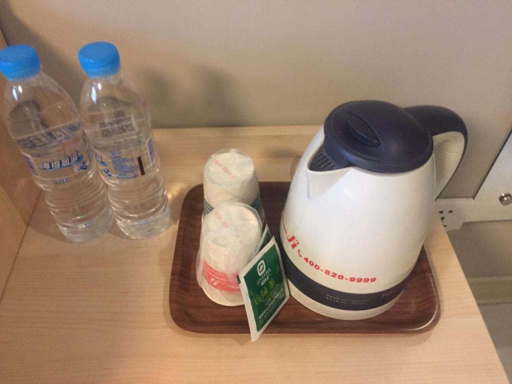 a tea kettle and two bottles of water on a tray at Jinjiang Inn Tianjin Xinkai Road in Tianjin