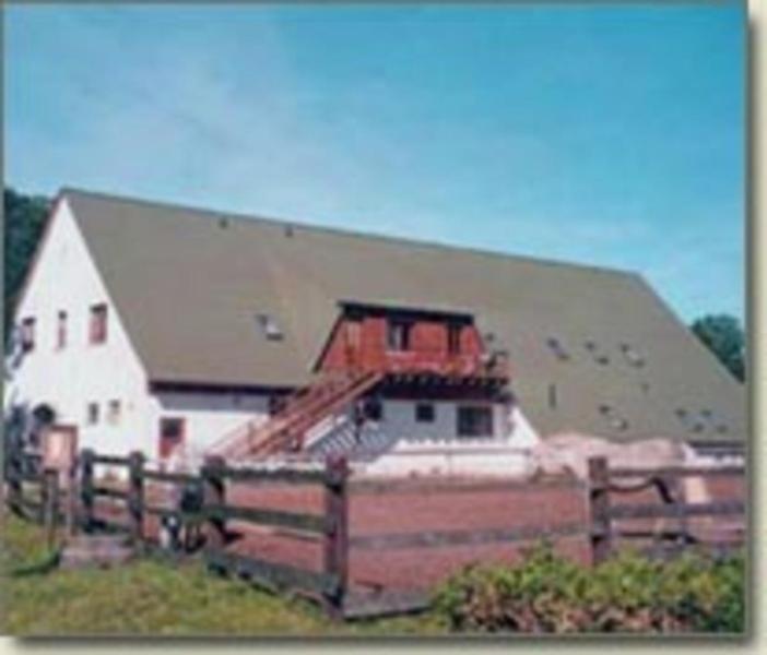 a large white barn with a fence in front of it at Pferdehof Ranzow in Ranzow