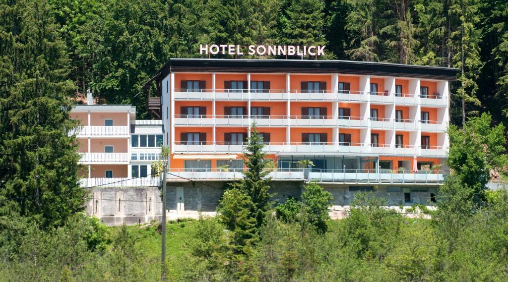 Un bâtiment avec un panneau d'entreprise d'hôtel en haut dans l'établissement Vitalhotel Sonnblick, à Egg am Faaker See