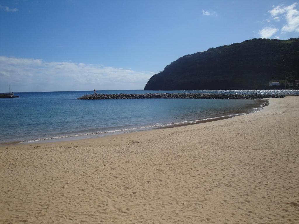 a sandy beach with the ocean and a person in the distance at Estacada Apartment in Machico