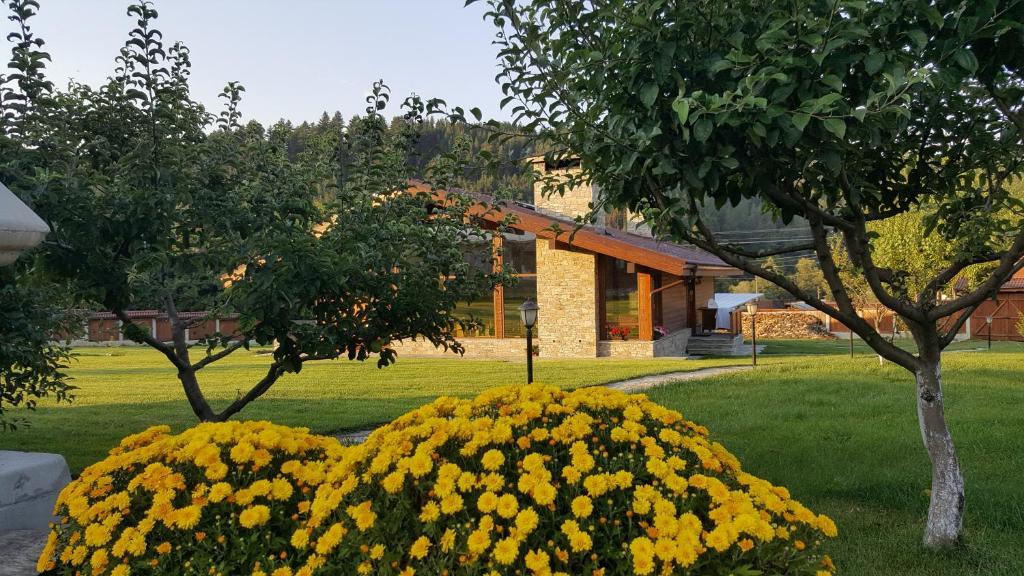 einen Garten mit gelben Blumen vor einem Gebäude in der Unterkunft Gostnici Holiday Home in Raslog