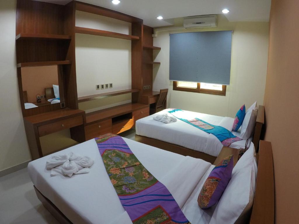 a hotel room with two beds and a mirror at The Supara in Bangkok