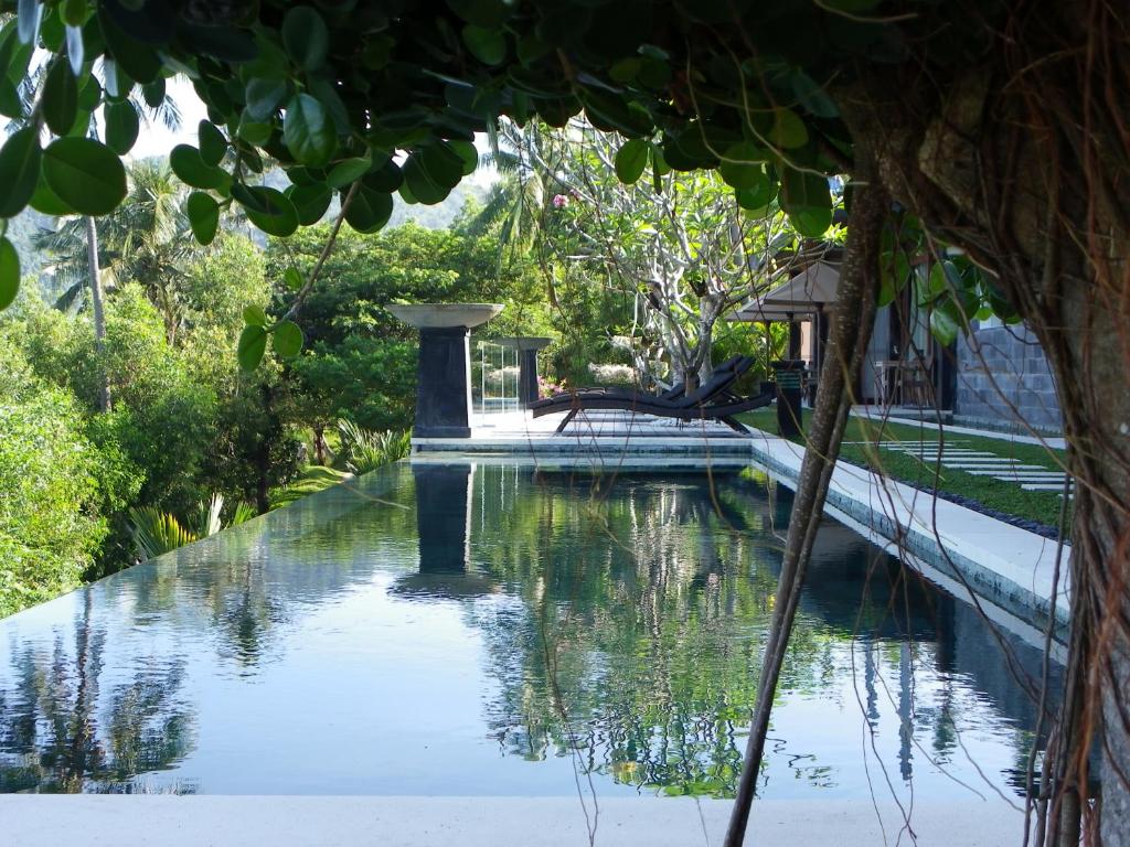 a swimming pool in a garden with trees at The Puncak Lombok in Senggigi