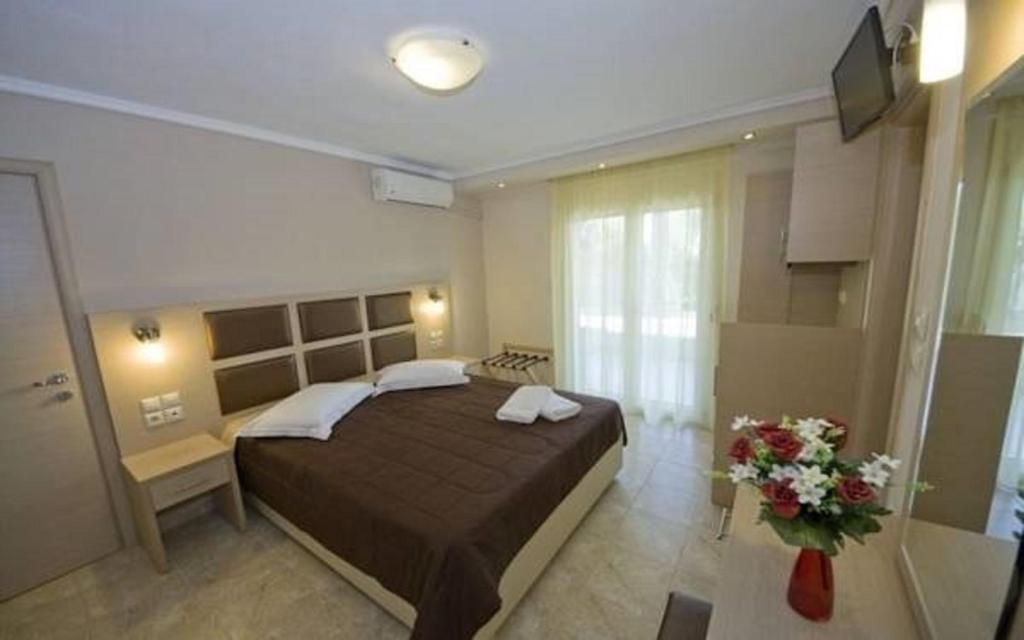 a bedroom with a large bed and a vase of flowers at Gaia Studios & Apartments in Nea Plagia