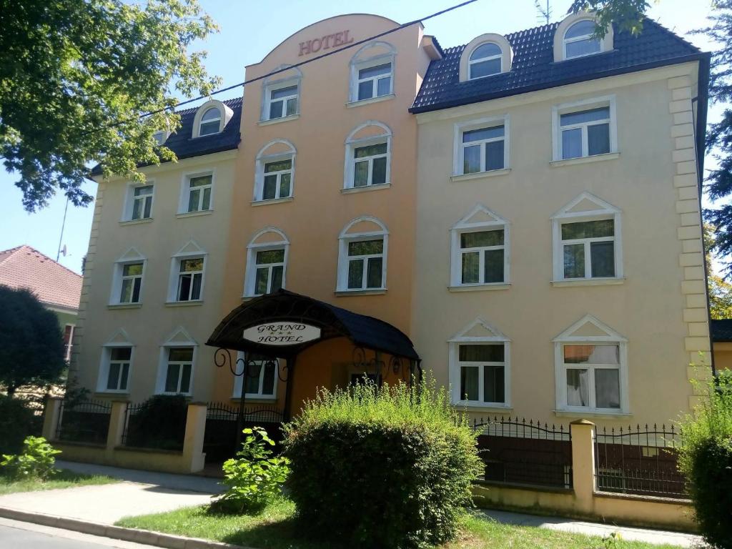 a large yellow building with a blue roof at Hotel Grand in Nové Zámky