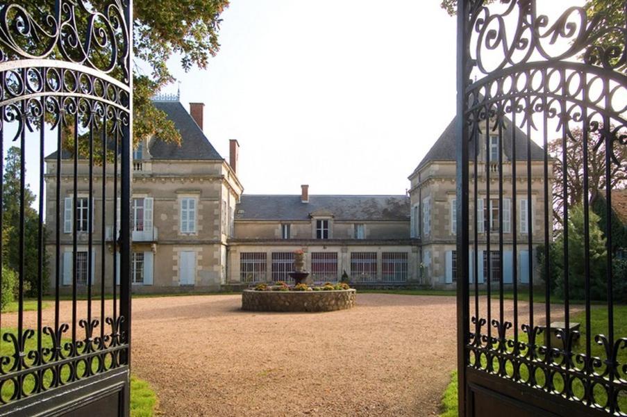 une porte ouverte menant à un grand bâtiment avec une cour dans l'établissement Château de Gerbe, à Saint-Rémy-en-Rollat