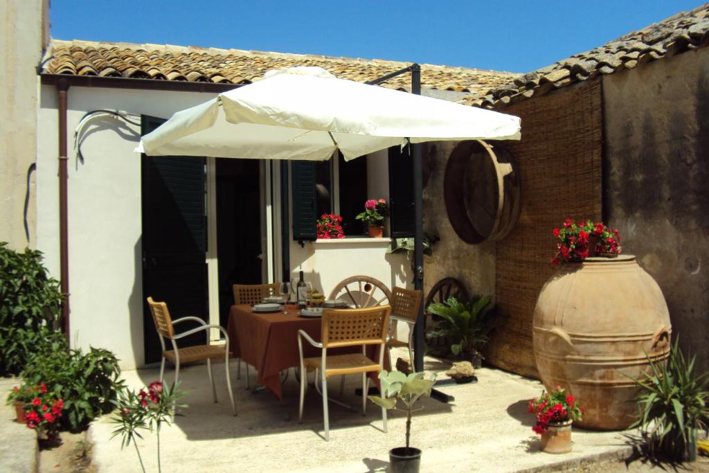 eine Terrasse mit einem Sonnenschirm, einem Tisch und Stühlen in der Unterkunft La Fattoria in Sciacca