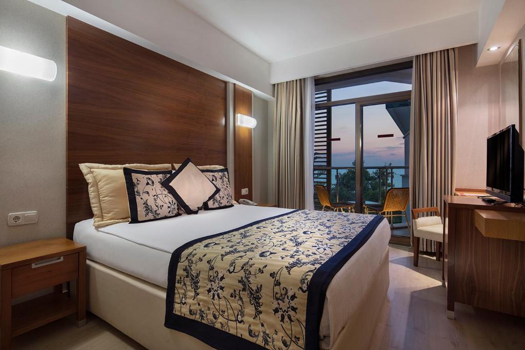 シダにあるTrendy Side Beach Hotelのベッド、デスク、テレビが備わるホテルルームです。