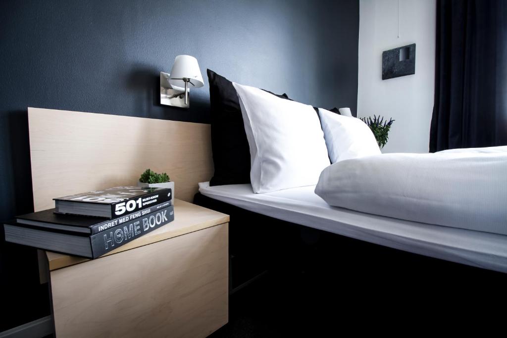 1 dormitorio con 1 cama y mesita de noche con libro en Teaterhotellet en Horsens