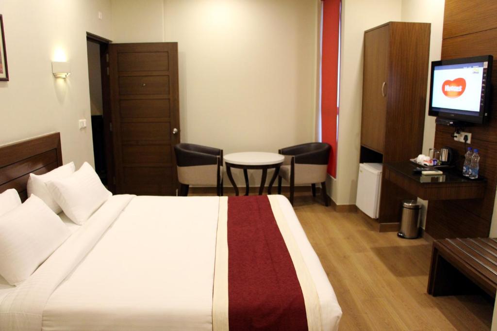 a hotel room with a bed and a table and a television at Hotel Dasaprakash in Agra