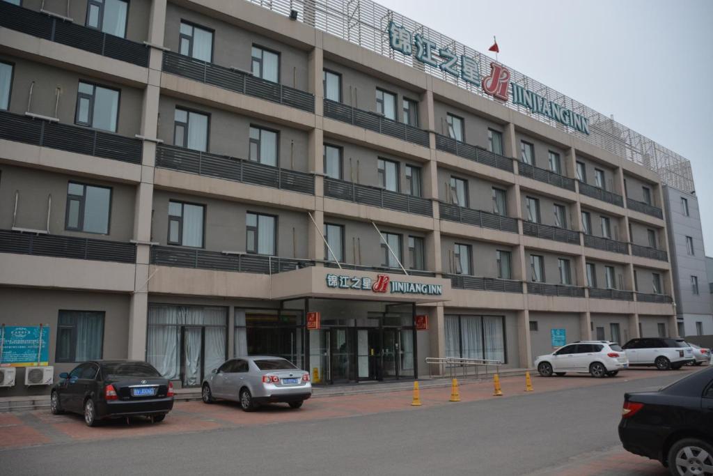 a large building with cars parked in front of it at JinJiang Inn Tianjin Steel Tube Company in Tianjin