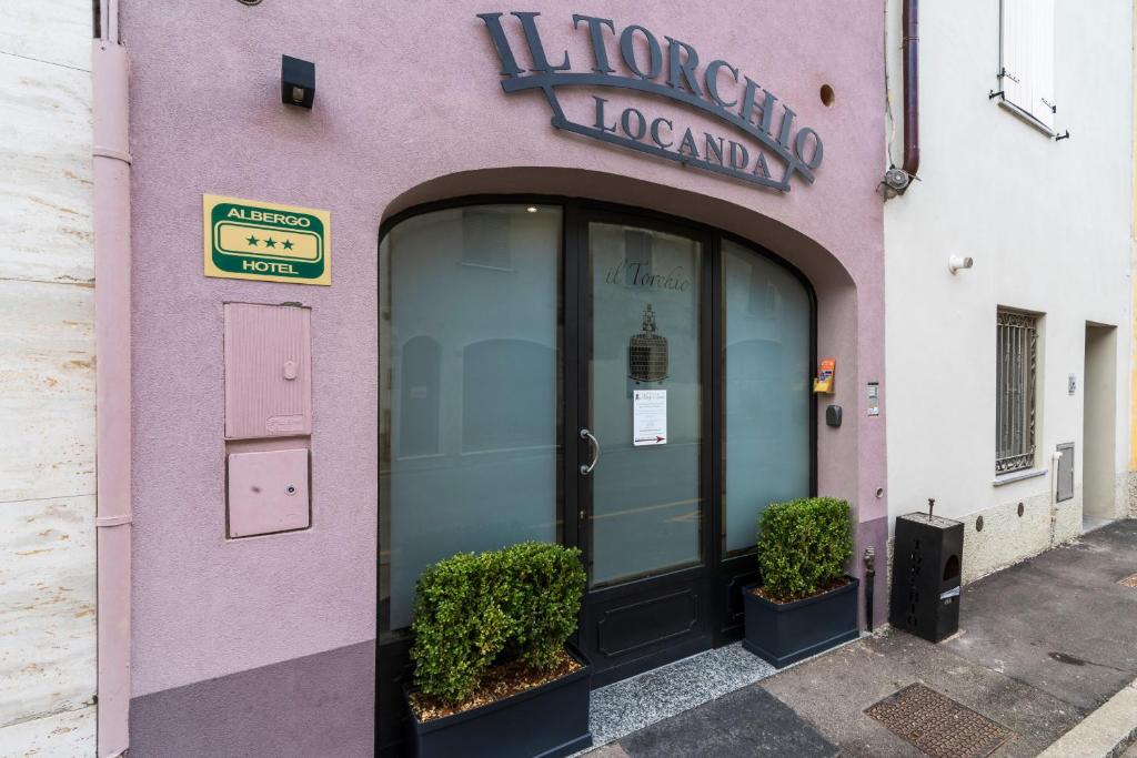 a pink building with a door and a sign on it at Albergo il Torchio in Pizzighettone