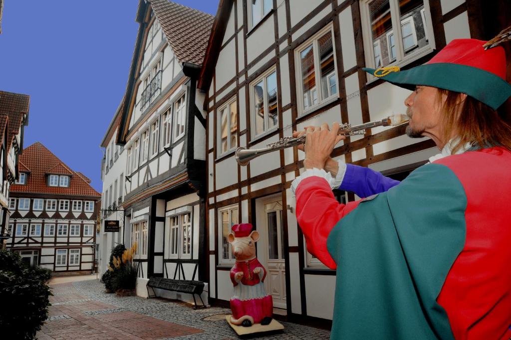 a woman playing a flute next to a building at Hotel La Principessa in Hameln